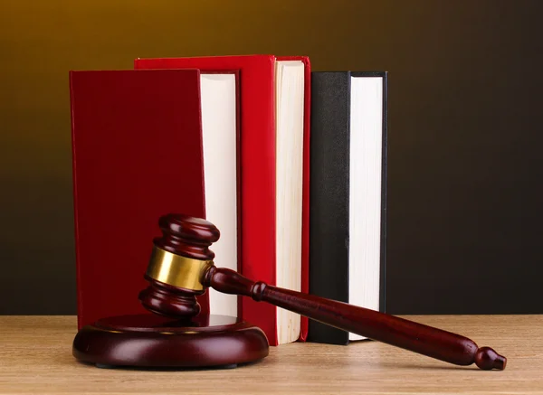 Judge's gavel and books on wooden table on brown background — Stock Photo, Image