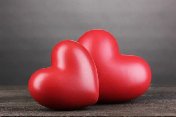 Два декоративных красных сердца на деревянном столе на сером фоне — стоковое фото