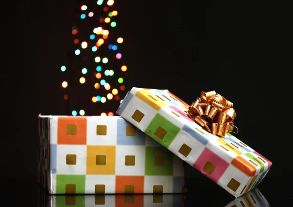 Open gift box with bokeh background on black — Stock Photo, Image