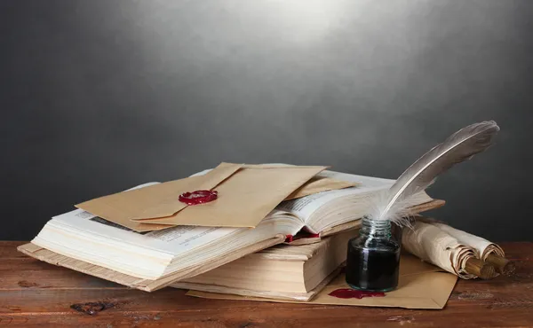 Stare książki, przewija, pióro, pióro i Kałamarz na drewnianym stole na szarym tle — Zdjęcie stockowe