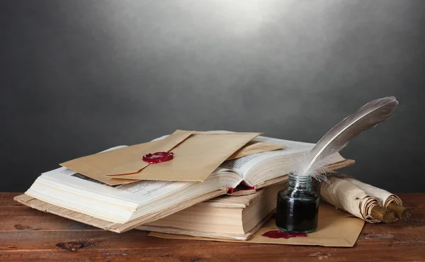 stock image Old books, scrolls, feather pen and inkwell on wooden table on grey background