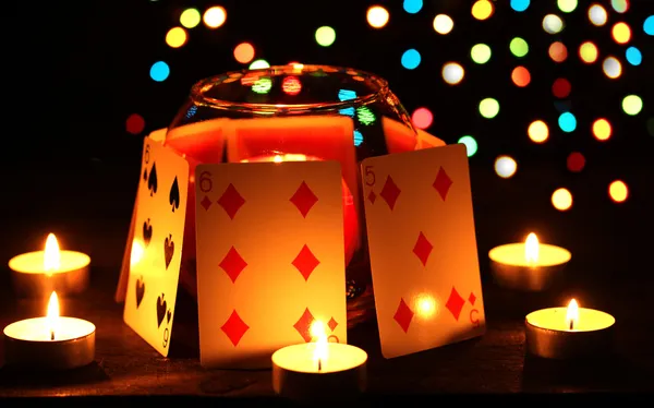 Velas e cartas de jogar na mesa de madeira no fundo brilhante — Fotografia de Stock
