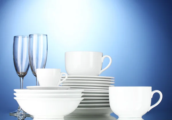 Lege kommen, borden, kopjes en glazen op blauwe achtergrond — Stockfoto