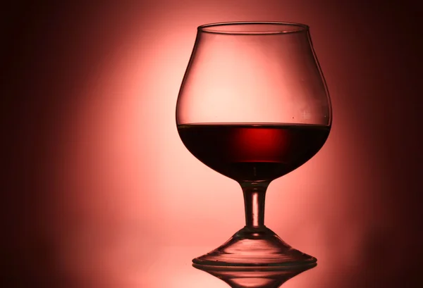 Glass of cognac on red background — Stock Photo, Image