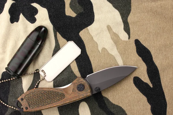 Армейские значки и нож на фоне камуфляжа — стоковое фото