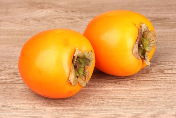 Two appetizing persimmons on wooden background — 图库照片