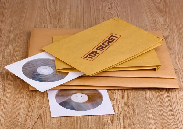 Enveloppes avec timbre top secret avec disques CD sur fond en bois — Photo