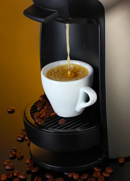 stock image Espresso machine pouring coffee in cup on brown background