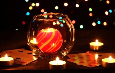 Candles and playing cards on wooden table on bright background clipart