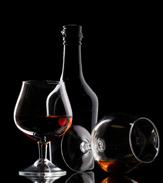Lunettes de brandy et bouteille sur fond noir — Photo