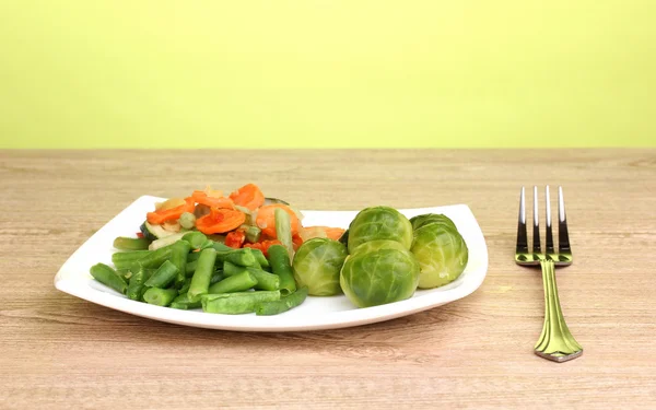 Verduras mixtas en plato sobre mesa de madera sobre fondo verde —  Fotos de Stock