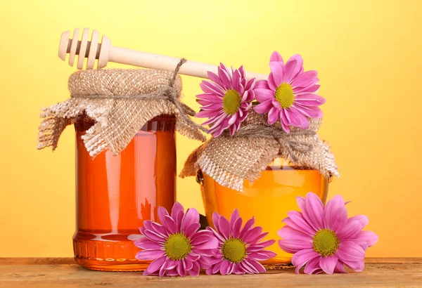 Miel dulce en frascos con rociador sobre mesa de madera sobre fondo amarillo —  Fotos de Stock