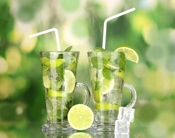 Cocktailgläser mit Limette und Minze auf grünem Hintergrund — Stockfoto