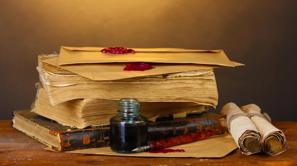 Libros antiguos, rollos, pluma de tinta y tintero sobre mesa de madera sobre fondo marrón —  Fotos de Stock