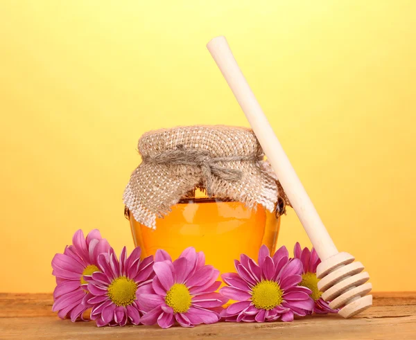 Söt honung i burk med drizzler på träbord på gul bakgrund — Stockfoto
