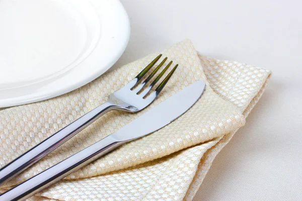 Fork, knife on napkin and plate isolated on white — Stock Photo, Image