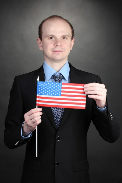 Amerikan bayrağı siyah arka planda tutan işadamı — Stok fotoğraf