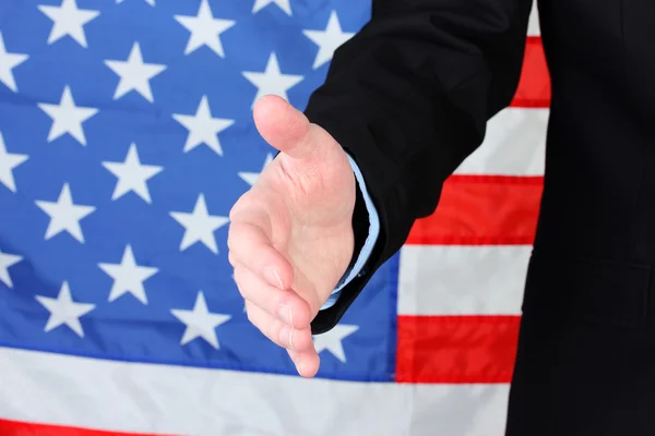 Amerikan bayrağı arka plan üzerinde bir el sıkışma için elini veren işadamı — Stok fotoğraf
