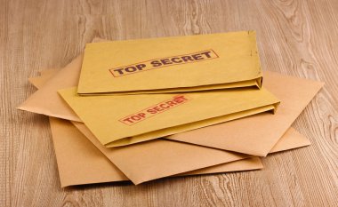 Envelopes with top secret stamp on wooden background clipart