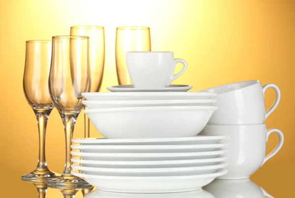 Puste miski, talerze, kubki i szklanki na żółtym tle — Zdjęcie stockowe