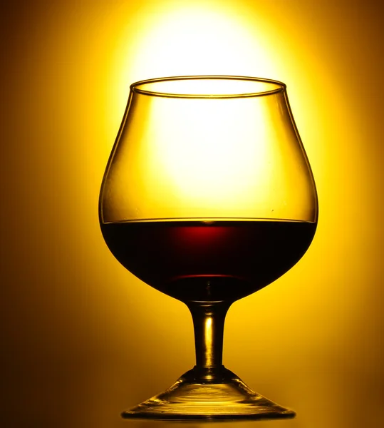 Glas cognac op gele achtergrond — Stockfoto
