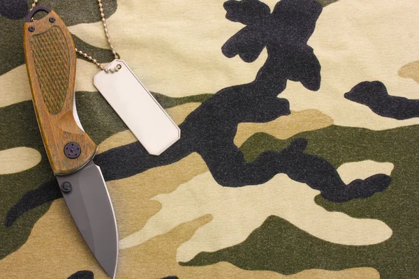 Армійські значки і ніж на камуфляжному фоні — стокове фото