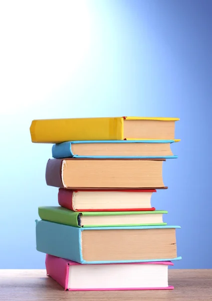 Bücherstapel auf Holztisch auf blauem Hintergrund — Stockfoto