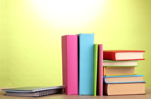 Livros com artigos de papelaria sobre mesa de madeira em fundo verde — Fotografia de Stock
