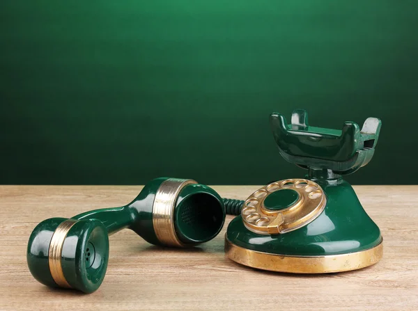 Retro telefoon op houten tafel op groene achtergrond — Stockfoto