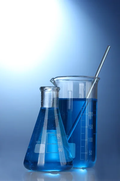 Tubos de ensaio com líquido azul sobre fundo azul — Fotografia de Stock