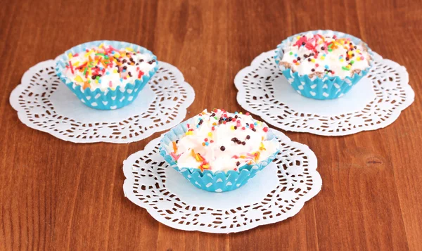 Cremige Cupcakes auf hölzernem Hintergrund — Stockfoto