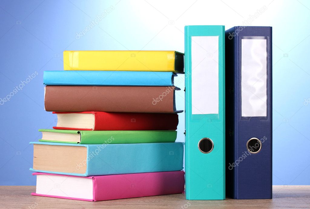 Bright office folders and books on wooden table on blue background