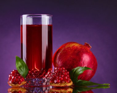 Ripe pomergranate and glass of juice on purple background clipart