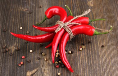 Red hot chili peppers tied with rope on wooden background clipart