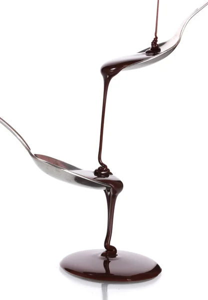 巧克力浇入一把勺子和从它到另一个勺子在白色隔离 — 图库照片