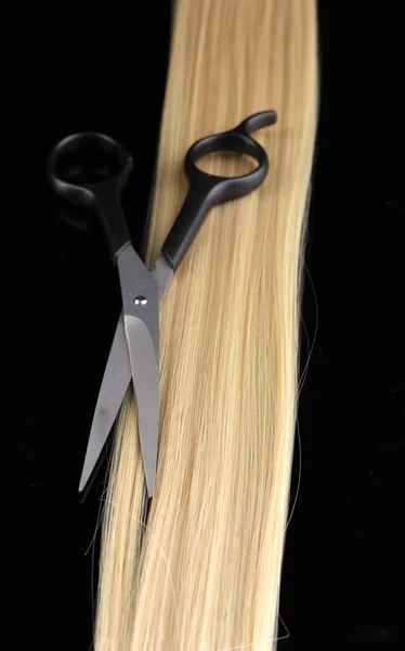 Lśniące włosy blond i nożyce do cięcia włosów na czarnym tle — Zdjęcie stockowe