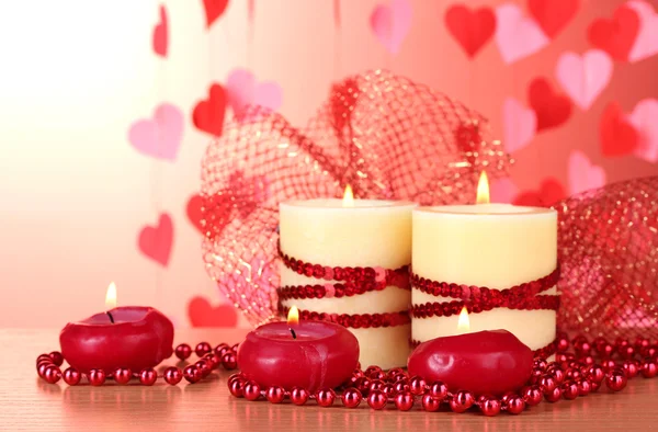 Schöne Kerzen mit romantischem Dekor auf einem Holztisch auf rotem Hintergrund — Stockfoto