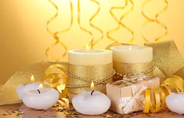 美丽的蜡烛，礼品和在黄色背景上的木桌上的装饰 — 图库照片