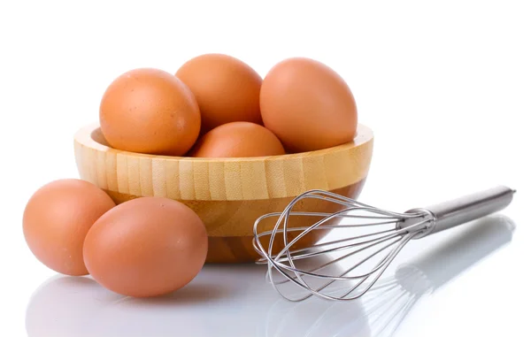 Metallbesen zum Aufschlagen von Eiern und braunen Eiern in Holzschüssel isoliert auf weiß — Stockfoto