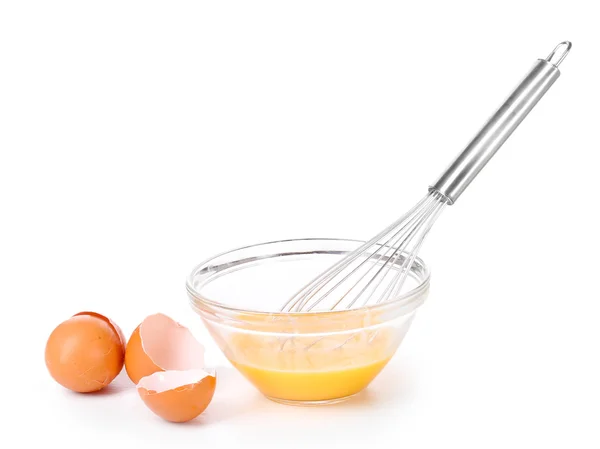 Batidor de metal para batir huevos y huevos en un bol aislado sobre blanco — Foto de Stock