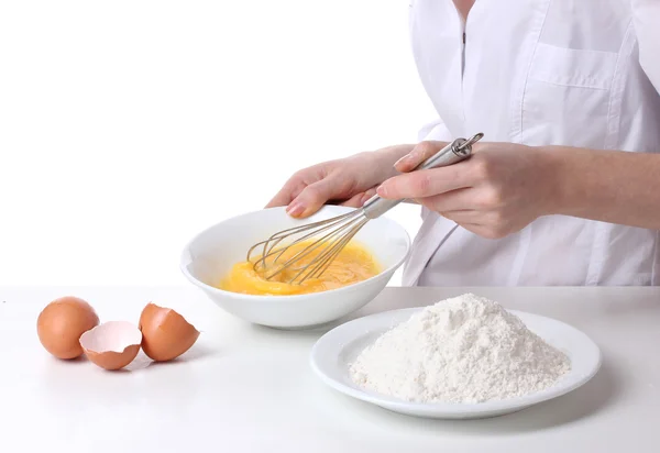 Mains féminines Mélanger les œufs dans un bol isolé sur blanc — Photo