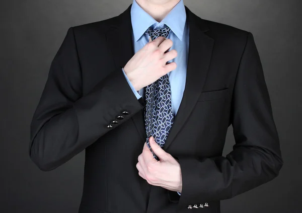 Podnikatel oprava kravatu na černém pozadí — Stock fotografie