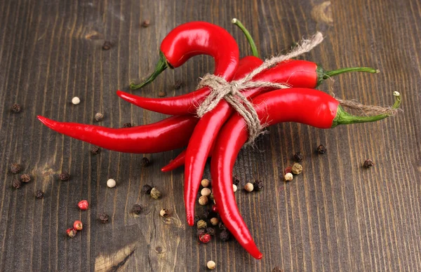 Red hot chili peppers tied with rope on wooden background — Stock Photo, Image