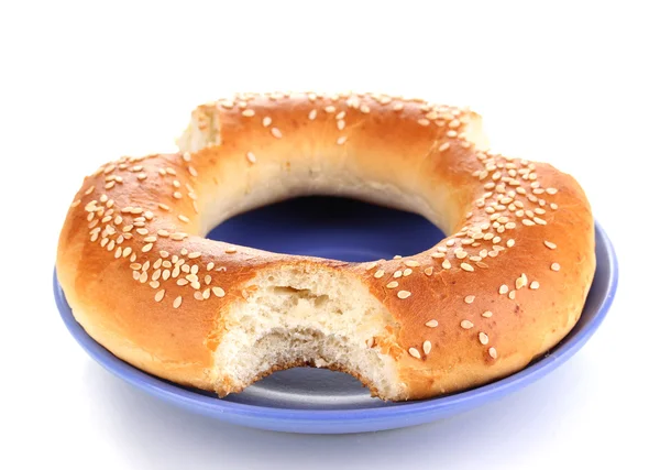 Gebissener Bagel mit Sesam auf Teller isoliert auf weißem — Stockfoto