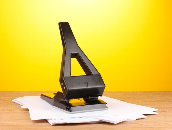 Buraco negro escritório perfurar com papel sobre fundo amarelo — Fotografia de Stock