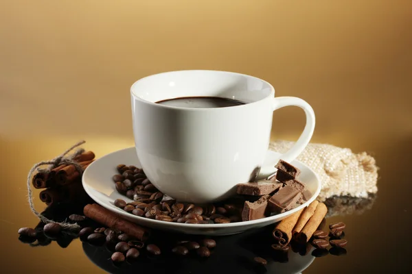 Kopje koffie en bonen, kaneelstokjes en chocolade op bruine achtergrond — Stockfoto