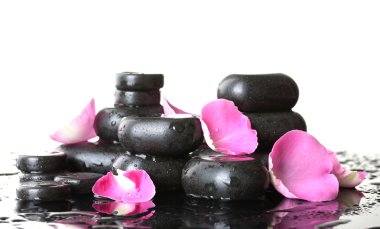 Spa stones with drops and rose petals on white background