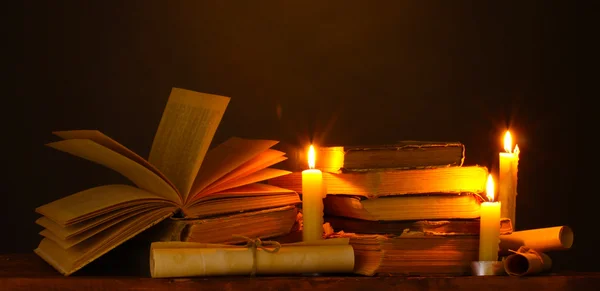 Montón de libros antiguos con vela y pergamino en la oscuridad — Foto de Stock