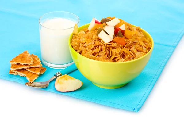 Tasty cornflakes in bowl with dried fruits and glass of milk on blue napkin — Stock Photo, Image