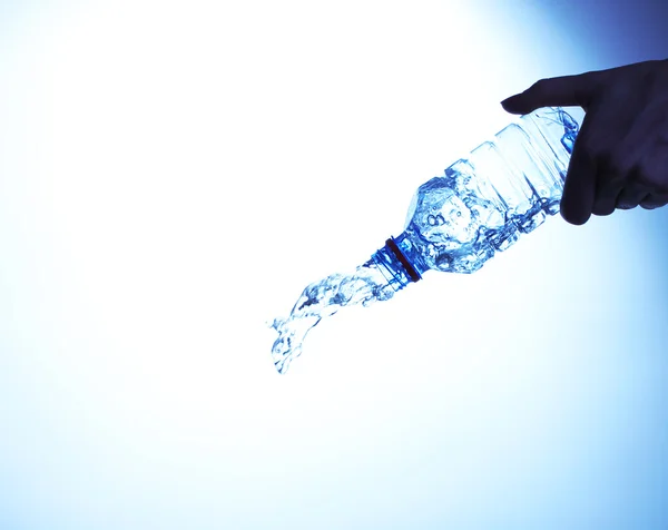 Water splashing out of bottle on blue background — Stock Photo, Image